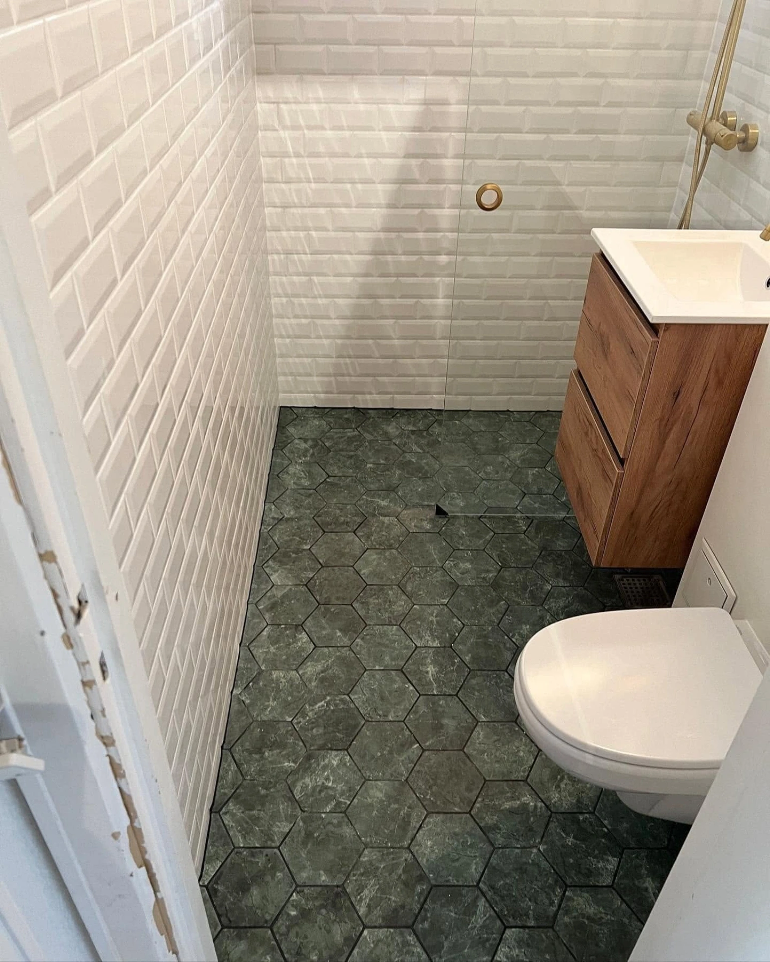 Badeværelse med vægfliser, toilet og vask med skab.