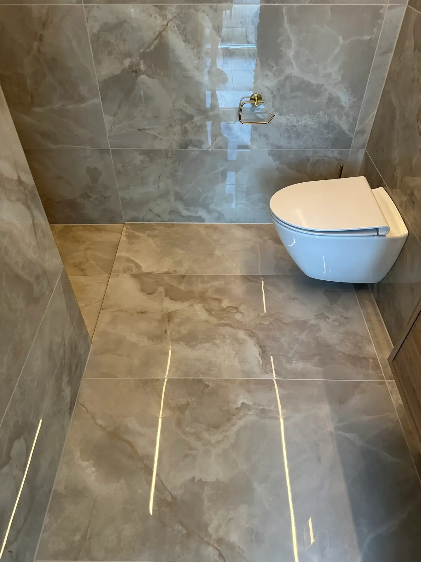 Moderne væg- og gulvfliser med vægtoilet i badeværelse.