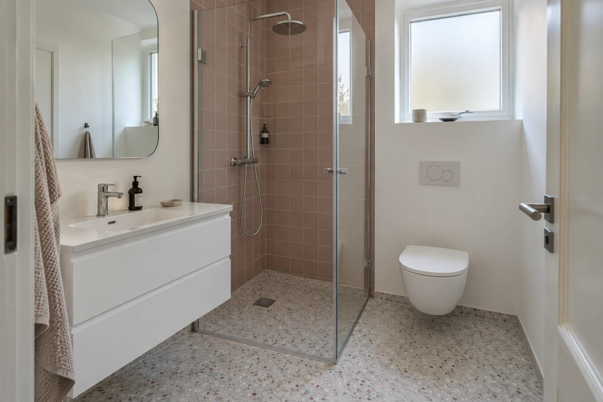 Badeværelse med bruseniche, vægtoilet og vaskeservant.