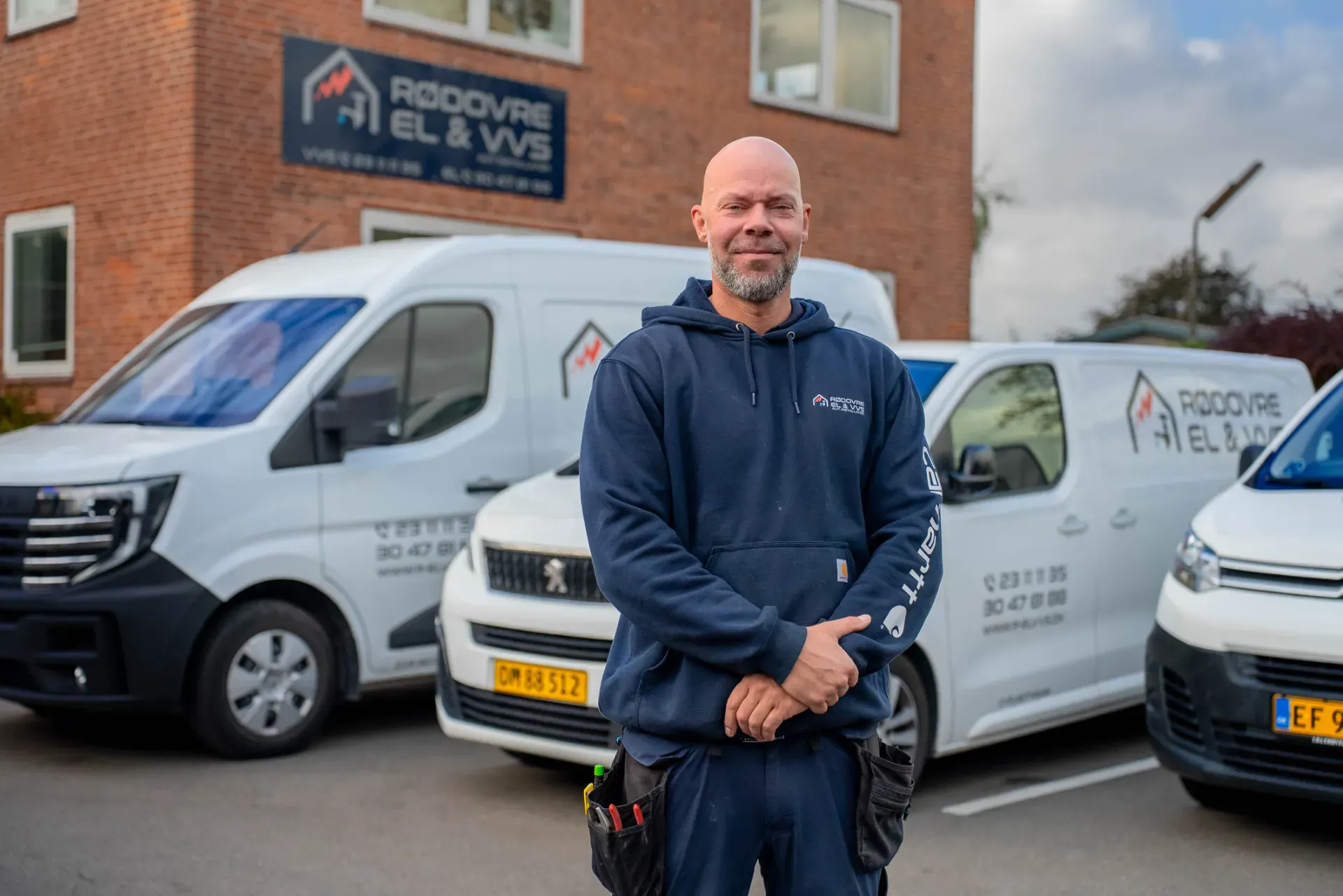 Mand står foran Rødovre El & VVS biler udenfor firmaets bygning.
