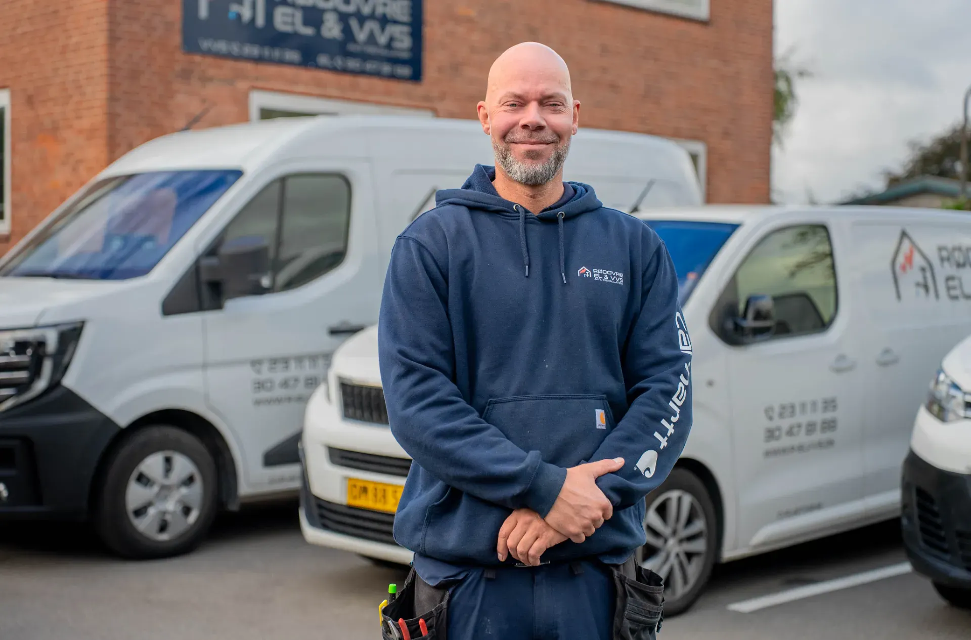 Mand står foran Rødovre El & VVS biler, klar til service.