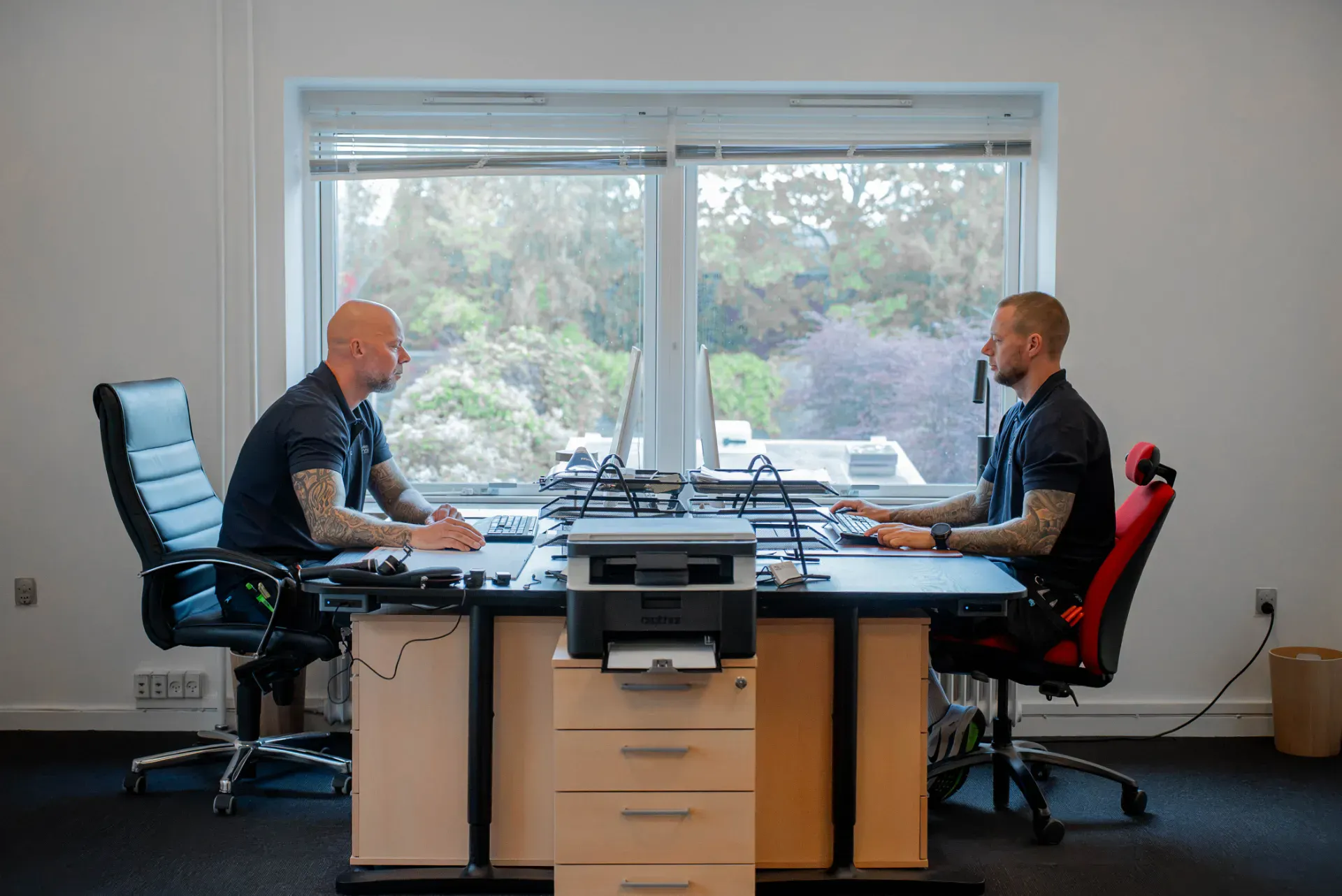 To mænd arbejder ved kontorbord i Rødovre El & VVS ApS kontor.