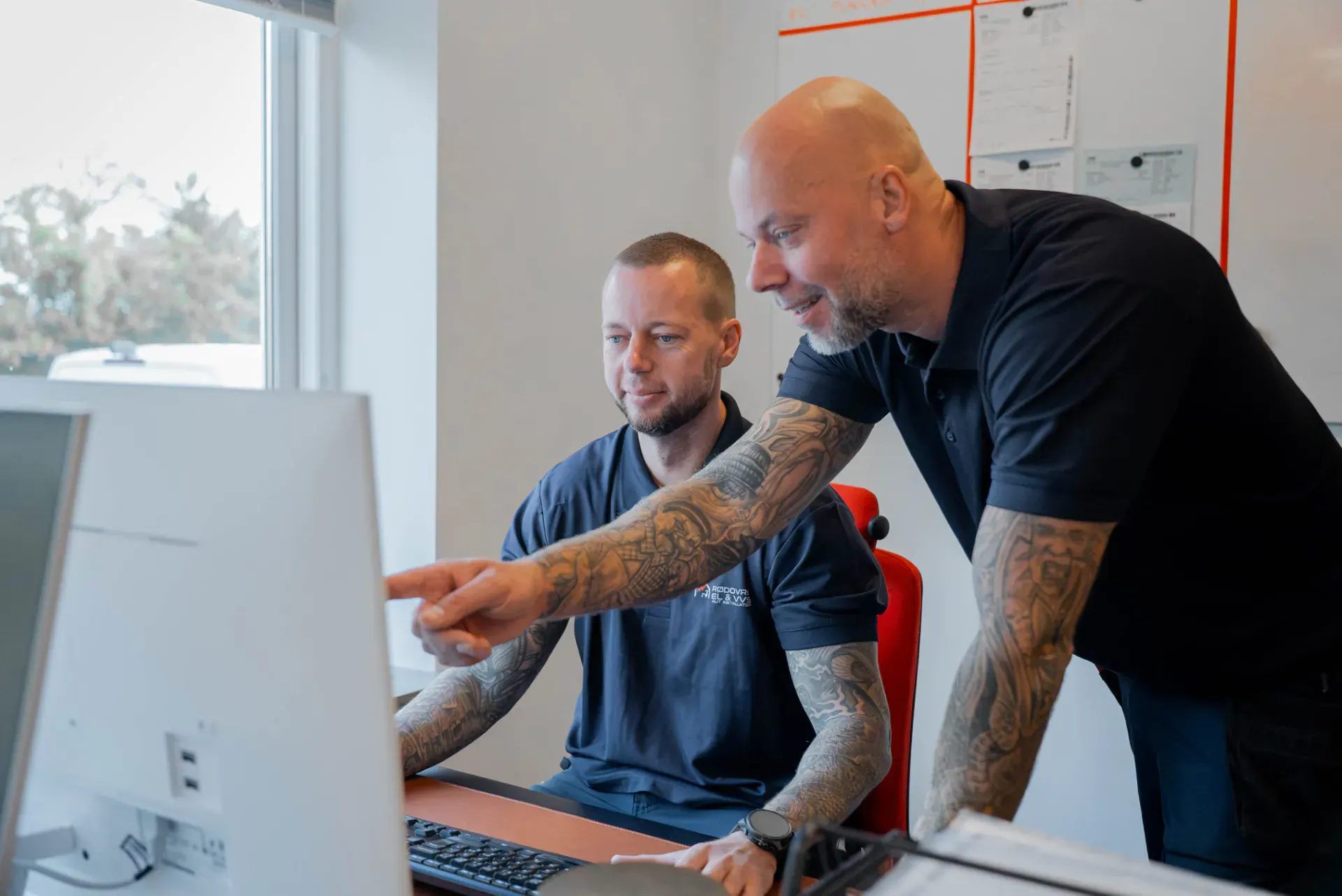To mænd arbejder sammen ved computer i VVS-firma kontor.